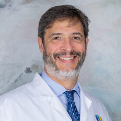 Portrait of a smiling middle-aged man in a white coat with a beard.