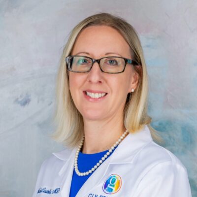Portrait of a smiling female doctor wearing glasses and a white coat.