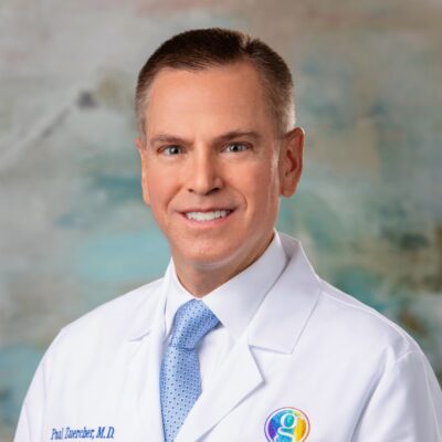 A professional headshot of a male doctor in a white coat.