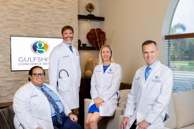 Gulfshore_Concierge_Medicine_2024_Group_Shot_@ ES9_Photography_2024-77 Four doctors in white coats smiling indoors.